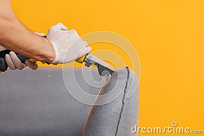 Dry cleaner& x27;s employee removing dirt from furniture in flat, closeup. Cleaning company using professional equipment. Stock Photo