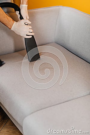 Dry cleaner's employee removing dirt from furniture in flat, closeup. Cleaning sofa with professional chemicals Stock Photo