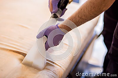 Dry cleaning of upholstery of a soft sofa with the help of a washing professional vacuum cleaner. large photo of the process Stock Photo