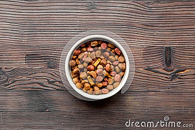 Dry dog food in bowl on wooden background top view Stock Photo