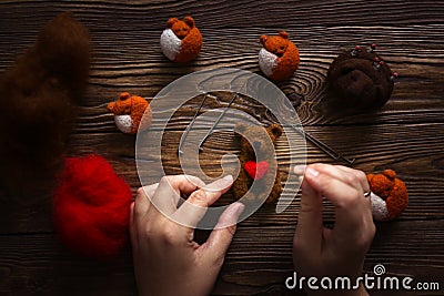 Hands with needles make bear with heart of wool Stock Photo