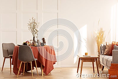 Flowers in vase on dining table covered with dark orange tablecloth Stock Photo