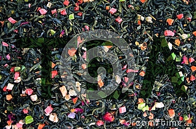 Dry green tea with flowers and pieces of fruit. Inscription on the background of tea top view Stock Photo