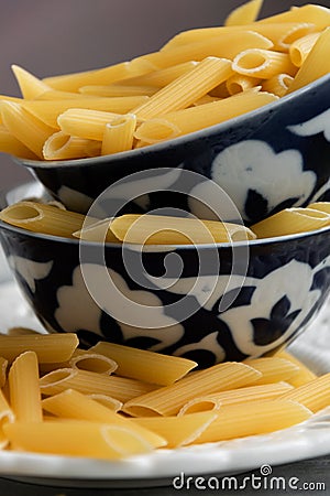 Dry penne pasta on blue vintage plate, whole uncooked ingredient Stock Photo