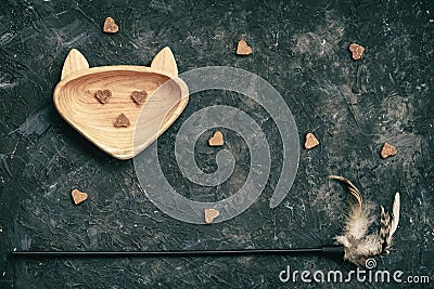 Dry pet food, treat in bowl shaped in head cat and toy on dark background top view. Concept care, feed pets Stock Photo