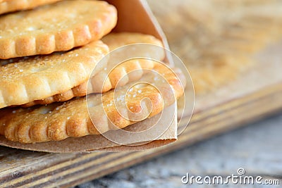 Dry salty cracker biscuits in a wrapping paper and wooden board. Crunchy savory cookies snack idea for children or adults Stock Photo