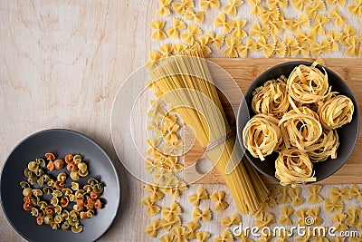 Dry spaghetti,fettuccine and sorprese in gray ceramic dishes on a bamboo cutting Board Stock Photo