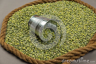 Dry split peas and a small bucket against a gray background. The green beans are framed by the ship`s rope. Close-up. Selective Stock Photo