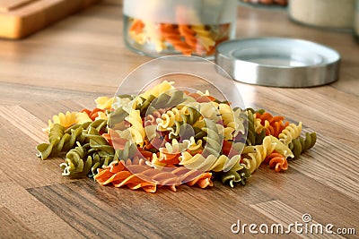 Dry tricolor rotini pasta on wooden kitchen desk Stock Photo
