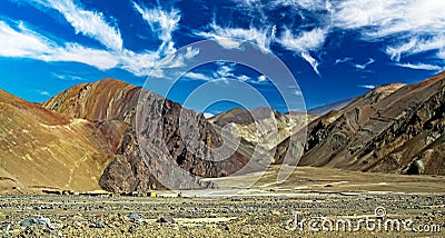 Dry unvegetated stony barren valley wide, gray rugged mountains, small mining settlement - Cordillera Copiapo, Atacama desert, Stock Photo