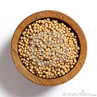 Dry white mustard seeds in dark wood bowl isolated on white. Stock Photo