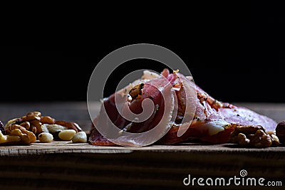 Dryed meat with nuts on a old chopping board. Stock Photo