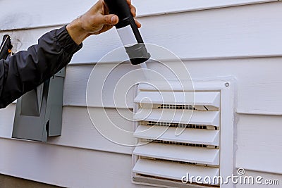 Dryer exhaust fan on side of house with plastic white trim with silicone Stock Photo