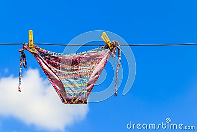 Drying female swimsuit hanging on rope against blue sky Stock Photo