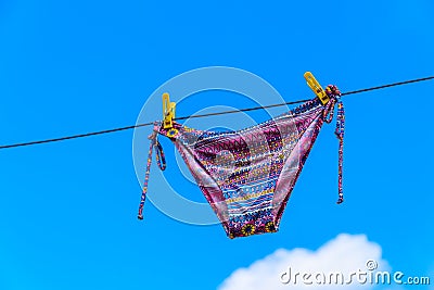 Drying female swimsuit hanging on rope against blue sky Stock Photo