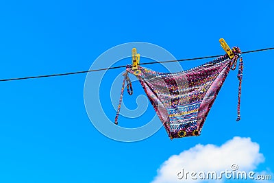 Drying female swimsuit hanging on rope against blue sky Stock Photo