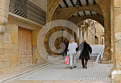 An elderly woman with a cane and her family are walking down the street Editorial Stock Photo