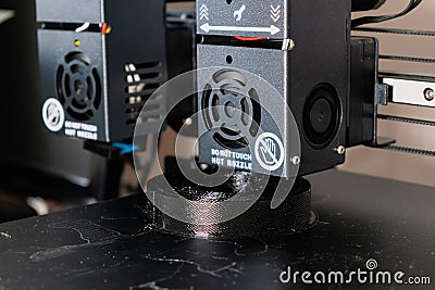 Dual extruder 3d printer printing a black model, idex technology Stock Photo