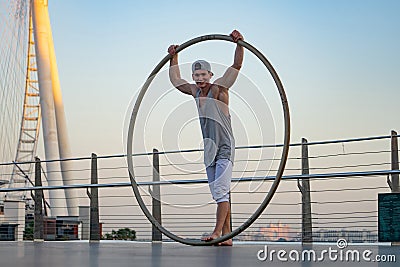 Dubai, February 2020. Cyr Wheel artist with Ferris wheel on background of Dubai during sunset Editorial Stock Photo