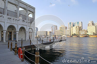 Al Seef Village at Bur Dubai. Al Seef old style area with people. Wooden promenade on water piles with view of old city - Creek. Editorial Stock Photo