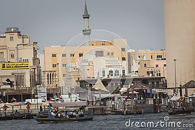 DUBAI, UAE - JANUARY 18, 2017 : Dubai Creek. Small ships and dhows line the Deira side of the creek while abras cross from Bur Du Editorial Stock Photo