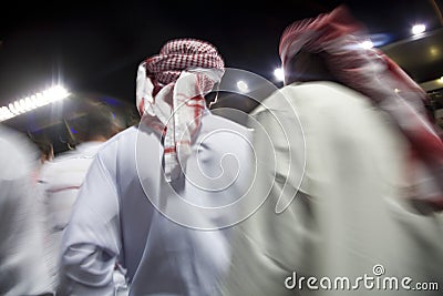 Dubai UAE small group of traditionally dressed Muslim men roaming grounds at Nad Al Sheba Stock Photo