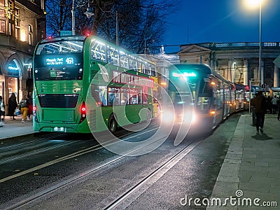 Dublin, Ireland - 20.12.2022: Busy traffic in the capital with double decker bus and Luas city tram in motion after dusk Editorial Stock Photo