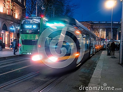 Dublin, Ireland - 20.12.2022: Busy traffic in the capital with double decker bus and Luas city tram in motion after dusk Editorial Stock Photo