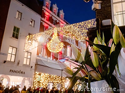 Dublin, Ireland - 20.12.2022: Flowers bouquet in focus and Decorated and illuminated Grafton street in the Irish capital out of Editorial Stock Photo