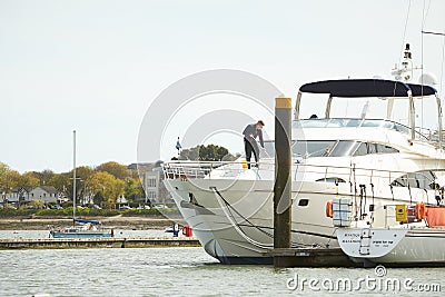 Dublin, Ireland - 04.23.2021: Man at work washing a boat at the marina. Yacht washing at the city pier. Editorial Stock Photo