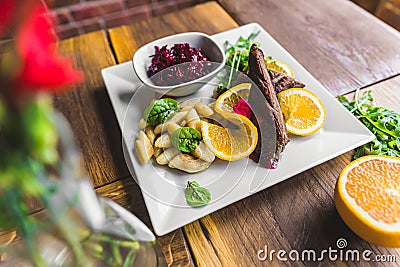 Duck fillet with potato dumplings and slices of juicy orange served on white plate. High angle shot. Indoor. Stock Photo