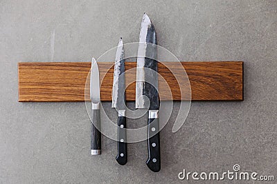 Dull Japanese kitchen knives stick on magnet cover with wood on concrete wall Stock Photo