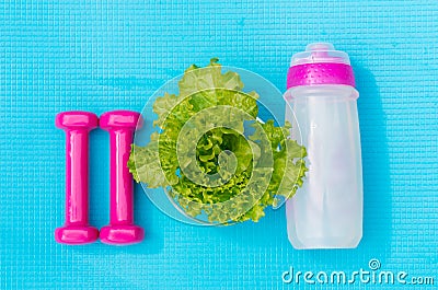 Dumbbells, bottle of water and salad leaves on yoga mat Stock Photo