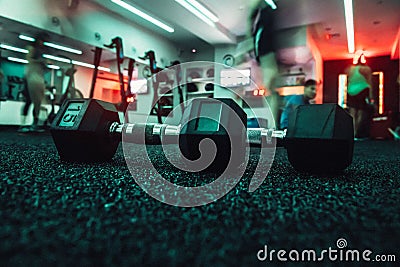 Dumbbells in gym with people doing sport workout. Stock Photo
