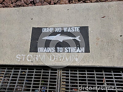 Dump no waste drains to stream anti-pollution sign at storm drain Editorial Stock Photo