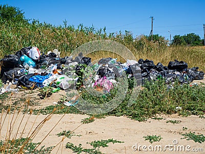 Dump on the river Bank. Garbage in nature. Lots of black bags of waste. Environmental problem of environmental pollution Editorial Stock Photo