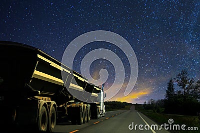 Dump truck big rig semi truck and trailer driving on a highway at night Stock Photo