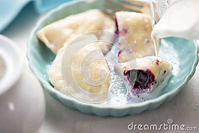 Dumplings with blueberries and cream. Sweet pierogi with berry fruit. Stock Photo