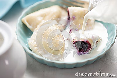 Dumplings with blueberries and cream. Sweet pierogi with berry fruit. Stock Photo
