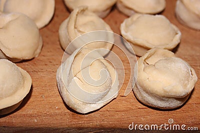 Dumplings on a wooden board. Top view on wooden table with homemade food. Uncooked handmade dumplings on a wooden plate Stock Photo