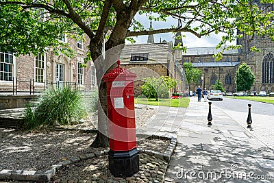 Traditional red post box that sits wonky at the Cathedral and Castle in Durham city centre Editorial Stock Photo