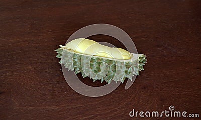 Durian peeled on the wooden table, one piece. Durian is an oval spiny tropical fruit. Stock Photo