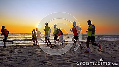 Football sport team is engaged in jogging training at sea at sunset Editorial Stock Photo