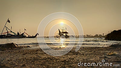 dusk when the sun sets on the edge of a romantic beach lagoon while looking at the shadow of the boats Stock Photo