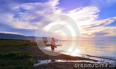 The setting sun, a woman walking on the beach Stock Photo