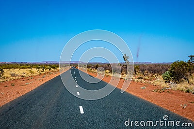Dust storms besides dark road leading through red sanded Australian landscape towards Karijini National Park Stock Photo