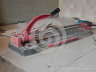 A dusty grungy tile cutter on freshly laid tiles - tiling tool / equipment Stock Photo
