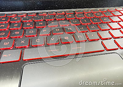 Dusty, static dust covered modern laptop gaming keyboard with red led backlight Stock Photo