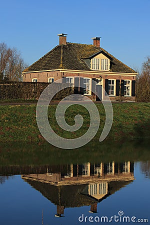 Dutch dike house mirrored in the water.