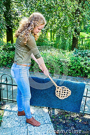 Dutch girl beating door mat with carpet beater Stock Photo